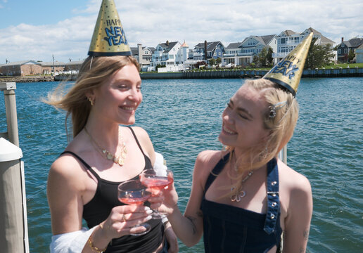 Blonde Girls Celebrating New Year in Party Hat by Ocean