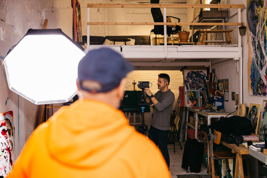 Filmmaker recording visual artist in studio

