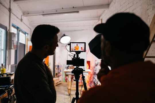 Crew monitors artist on camera screen

