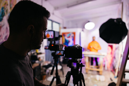 Cameraman films artist teaching in studio

