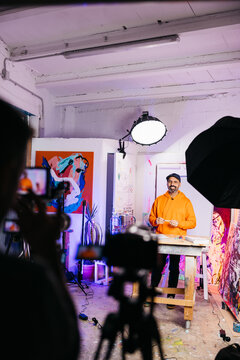 Smiling artist recorded in colorful studio

