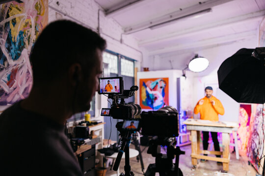 Cameraman records smiling artist in studio


