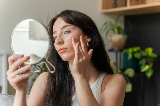 Woman Touching Face While Looking In Mirror