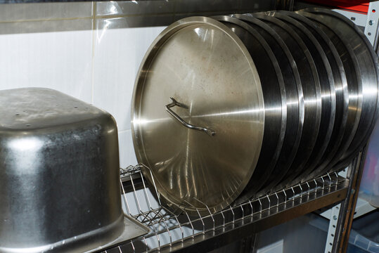 Metal cooking pots and lids organized on a kitchen shelf