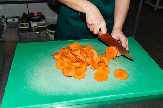 Person chopping carrots in a kitchen setting