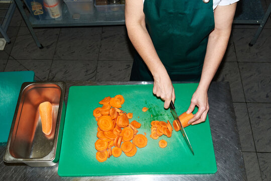 Person chopping carrots in a kitchen setting