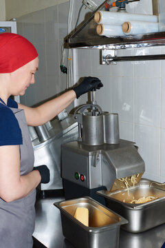 Woman operates cheese shredding machine in commercial kitchen