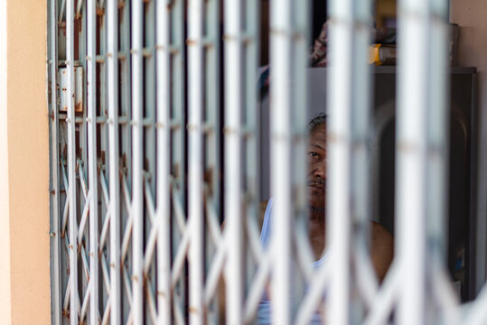 Elderly man seen through iron gate in quiet reflection