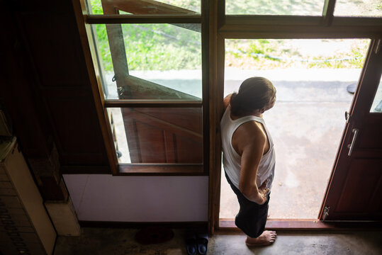 Elderly man standing at the doorway in early morning light