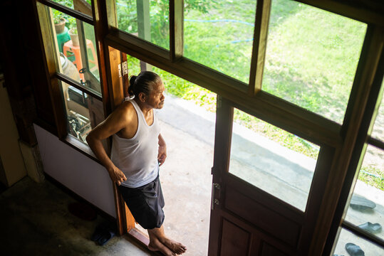 Elderly man standing at the doorway in early morning light