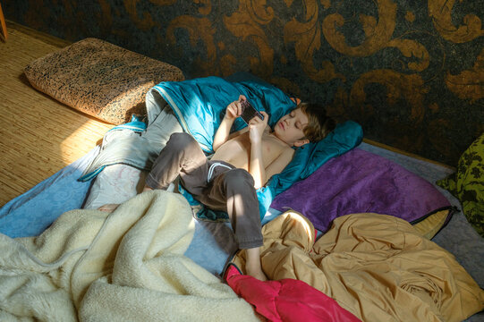 boy with phone lying on blanket