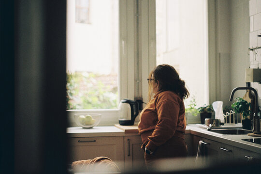 Woman Looking Out Kitchen Window
