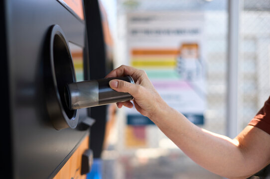 Person recycling aluminium can at a modern recycling station