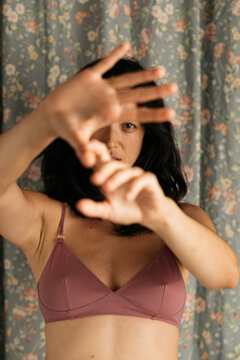 Woman in mauve bra raising hands to camera