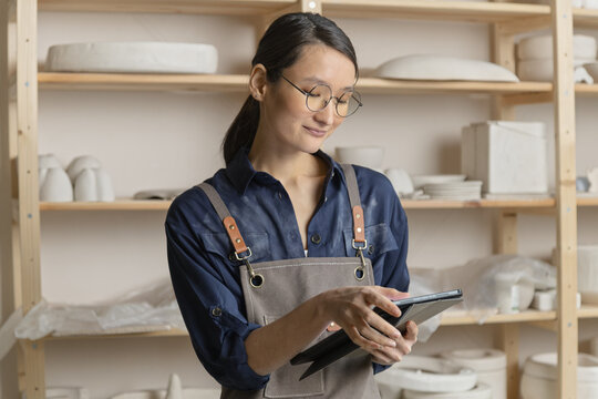 Portrait of ceramic artist using computer tablet in studio