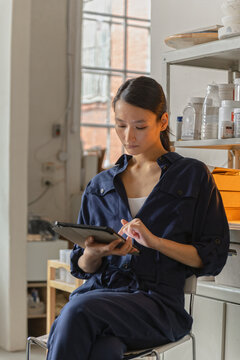 Portrait of ceramic artist using computer tablet in studio