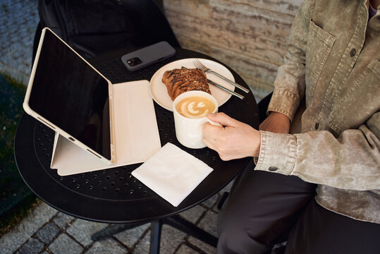 Enjoying coffee while working on a tablet at an outdoor cafe