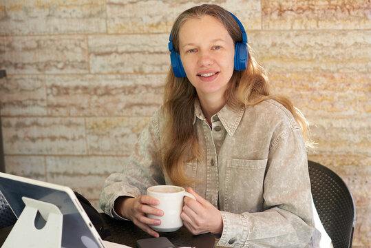 Woman using technology while enjoying a drink in a cozy workspace
