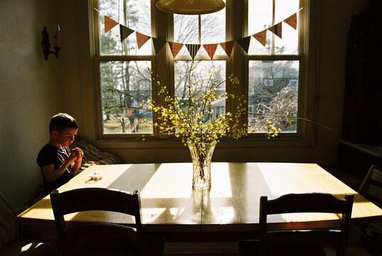 Candid film moment of child sitting at kitchen table
