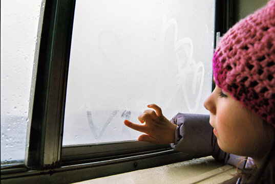 Child draws hearts on a foggy ferry window  in winter