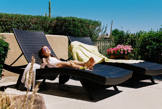 Child relaxes in the sun on chaise lounge 