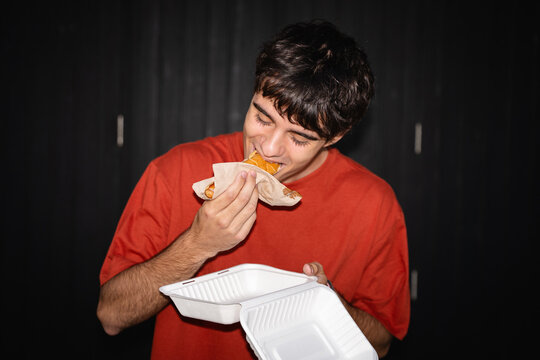 Young man enjoying a hot dog on the street. Flash, UGC, real lifestyle