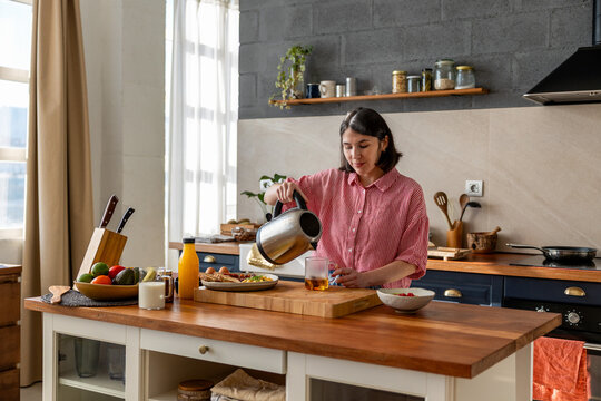 young girl making tea in a brightly lit kitchen in the morning