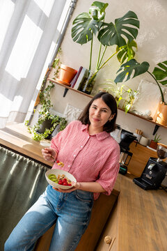 happy woman eating a delicious bowl of cereal and yogurt