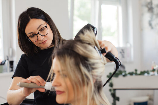 Hair Stylist Blow-Drying Client&rsquo;s Hair in Salon