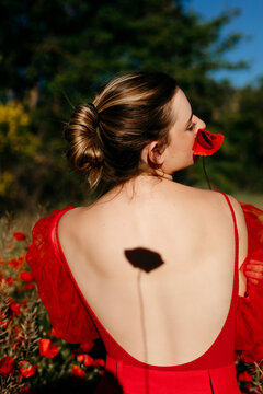 Young woman wit poppy flower and shadow of poppy in her back