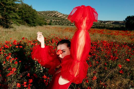 Woman posing in poppy field wearing red clothes