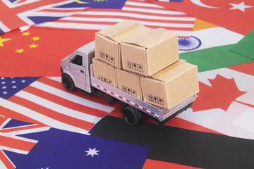 Many cardboard boxes on different national flags and lorry truck. Global trading, shipping and tariffs concept.