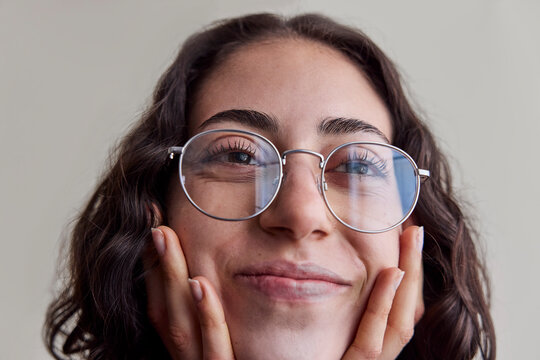 Young woman wearing eyeglasses in natural light smiling