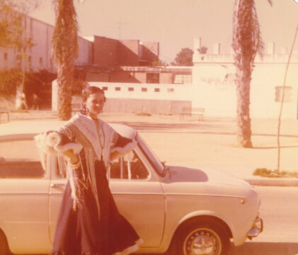Woman in Traditional Dress Posing With Classic Car 
