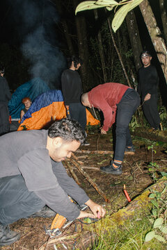 Group sets up camp in forest during nighttime adventure