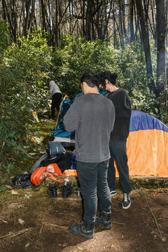 Friends setting up tents in a lush forest during daytime