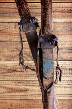 Antique wooden skis with leather strap bindings against a rustic wooden background