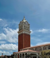 Fototapeta premium A historic clock tower stands tall against a blue sky with white clouds