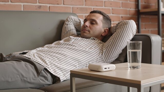 Man resting on couch with glass of water