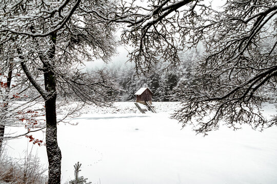 Snow covered Tajch Klinger lake with wooden cabin in winter Banska Stiavnica Slovakia