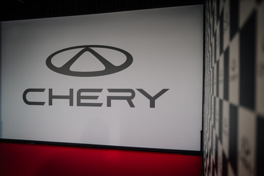 Chery logo displayed prominently on a wall during a brand launch event with a checkered background design