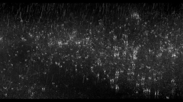 Realistic rain drops hitting the ground creating beautiful water splashes on a dark black background. Perfect cinematic rain overlay for video editing, visual effects, films, trailers, music videos