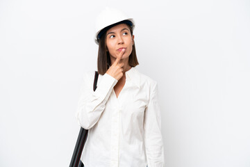 Young architect woman with helmet and holding blueprints isolated on white background having doubts...