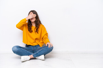 Young caucasian woman sitting on the floor isolated on white wall covering eyes by hands. Do not want to see something © luismolinero