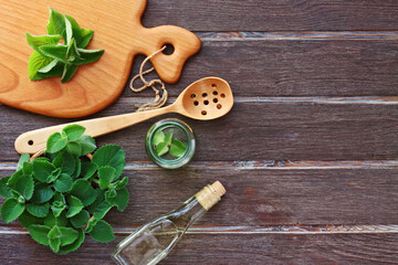 Fresh Mint Leaves Oil Bottle and Wooden Spoon on Table