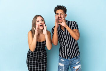 Naklejka premium Teenager caucasian couple isolated on blue background shouting and announcing something