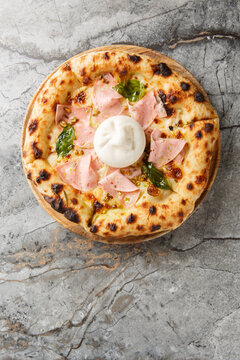 Authentic Italian pizza with mortadella sausage and burrata cheese, close-up, on a wooden board on a table. Vertical top view from above