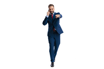 Fototapeta premium Confident businessman walking and pointing finger while talking on phone