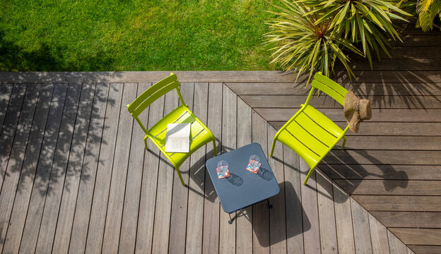 Terrasse dans un petit jardin paysag&eacute; et ses plantes vertes au milieu du gazon.