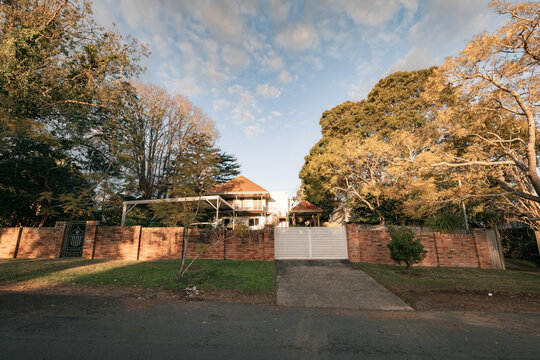 Large house in a leafy suburban street glowing in afternoon sunlight